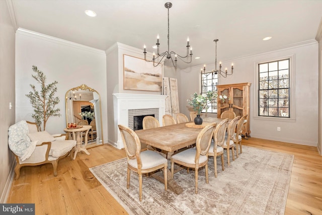 dining space with light wood-type flooring, a brick fireplace, baseboards, and crown molding