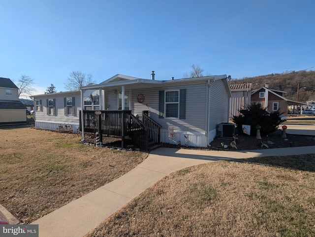 manufactured / mobile home with a porch, a front yard, and central air condition unit