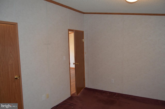 carpeted empty room with ornamental molding and a textured ceiling