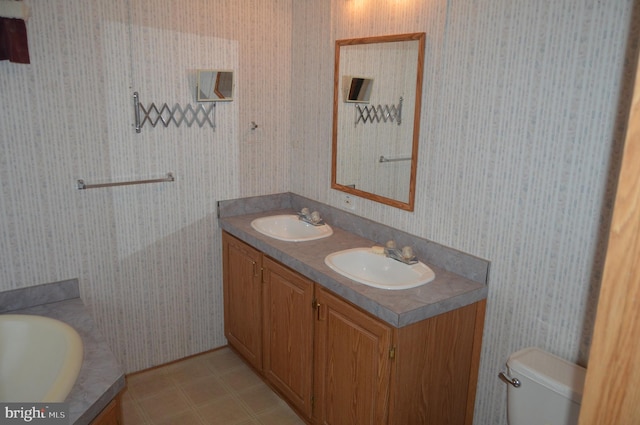 full bath with double vanity, wallpapered walls, toilet, and a sink