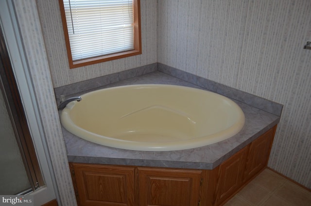 bathroom featuring wallpapered walls, a bath, and tile patterned floors