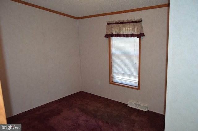 spare room featuring visible vents, dark carpet, and crown molding