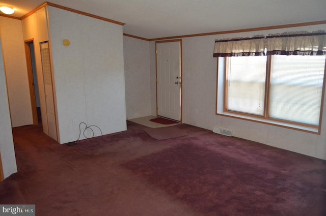 carpeted spare room featuring visible vents and crown molding