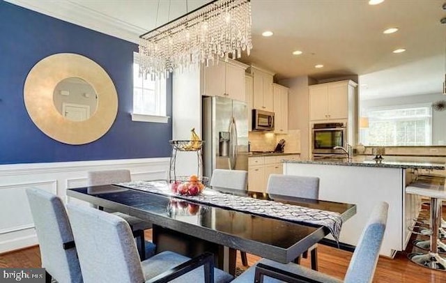 dining area with a decorative wall, a wainscoted wall, recessed lighting, dark wood-style flooring, and ornamental molding