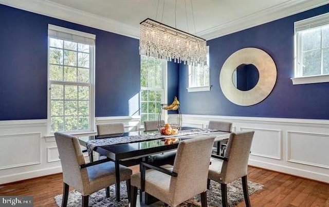 dining room with wainscoting, crown molding, a notable chandelier, and wood finished floors