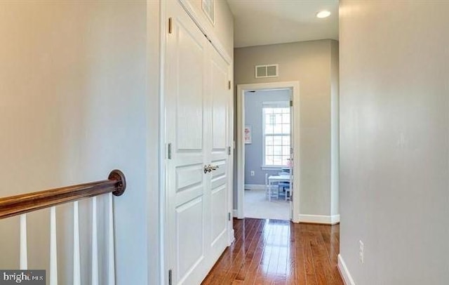 corridor with baseboards, visible vents, and dark wood-type flooring