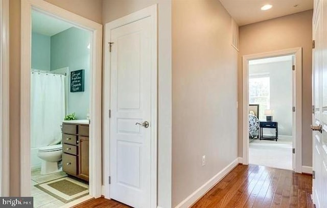 hall with baseboards, hardwood / wood-style floors, and recessed lighting