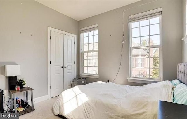 bedroom with carpet flooring, a closet, multiple windows, and baseboards