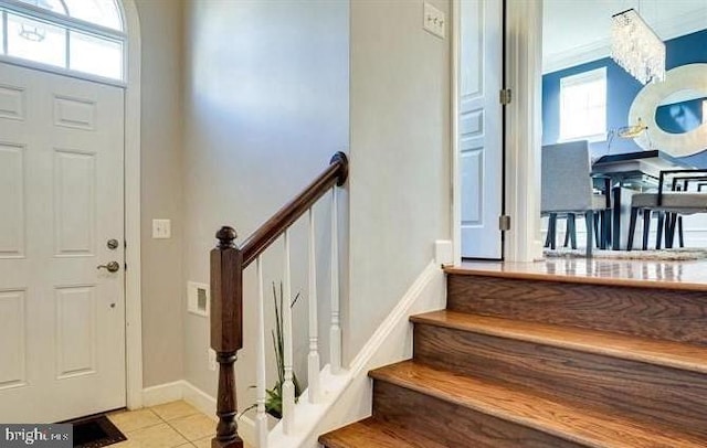 tiled entryway with stairs, plenty of natural light, and baseboards