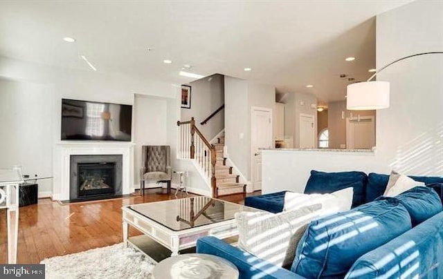 living room featuring recessed lighting, a fireplace, stairway, and wood finished floors