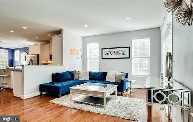 living area featuring light wood-type flooring, baseboards, and recessed lighting