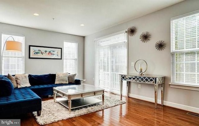 living area with visible vents, baseboards, and wood finished floors