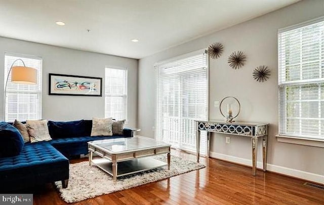 living area with wood finished floors, visible vents, and baseboards