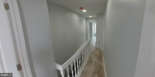 hallway featuring wood finished floors, an upstairs landing, and recessed lighting