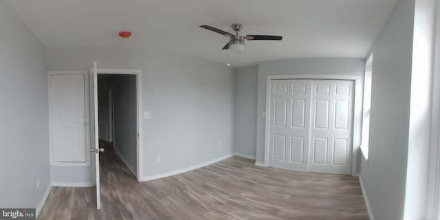 unfurnished bedroom featuring a closet, wood finished floors, a ceiling fan, and baseboards