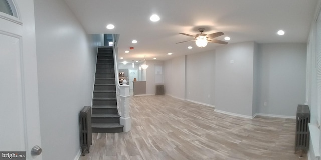 basement with baseboards, light wood-style floors, stairway, and radiator