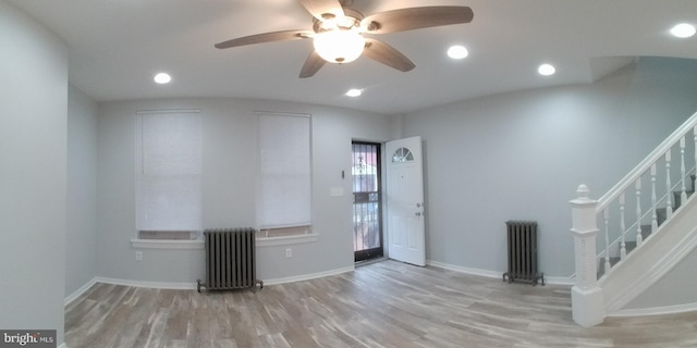 interior space featuring stairs, baseboards, wood finished floors, and radiator