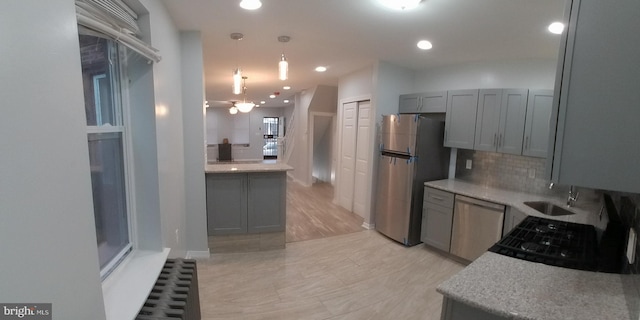 kitchen featuring tasteful backsplash, dishwasher, freestanding refrigerator, gray cabinets, and a sink