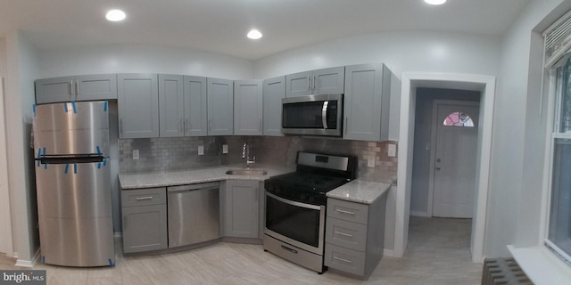 kitchen with stainless steel appliances, a sink, gray cabinets, tasteful backsplash, and radiator heating unit