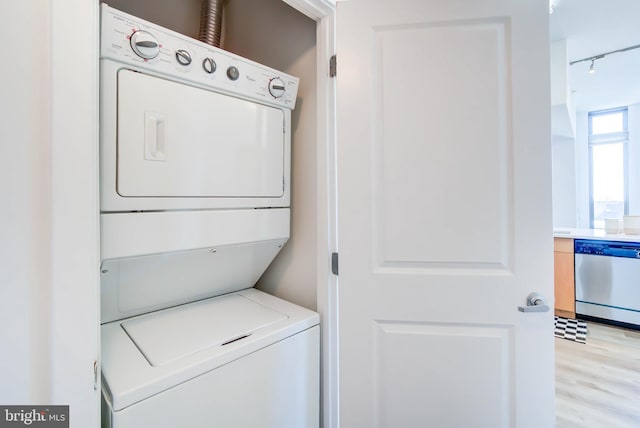 clothes washing area featuring stacked washer and dryer, light wood finished floors, and laundry area