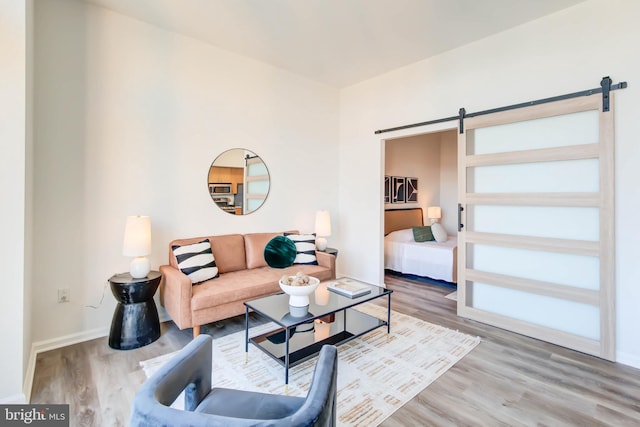 living room with a barn door, baseboards, and wood finished floors