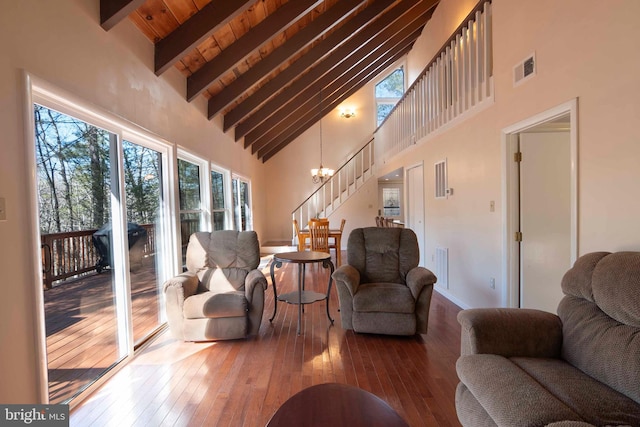 living area with wood-type flooring, stairs, a chandelier, and beam ceiling