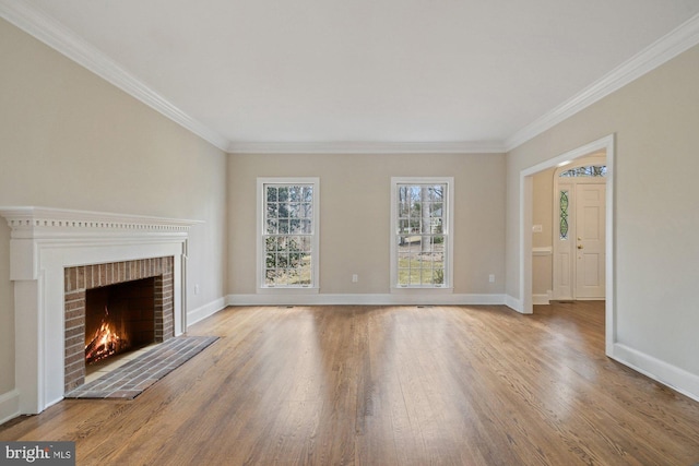 unfurnished living room with a brick fireplace, baseboards, wood finished floors, and ornamental molding