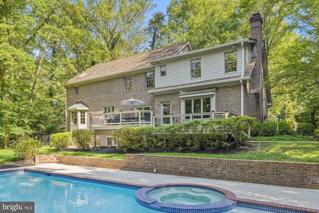 rear view of house with a chimney, fence, a deck, and brick siding