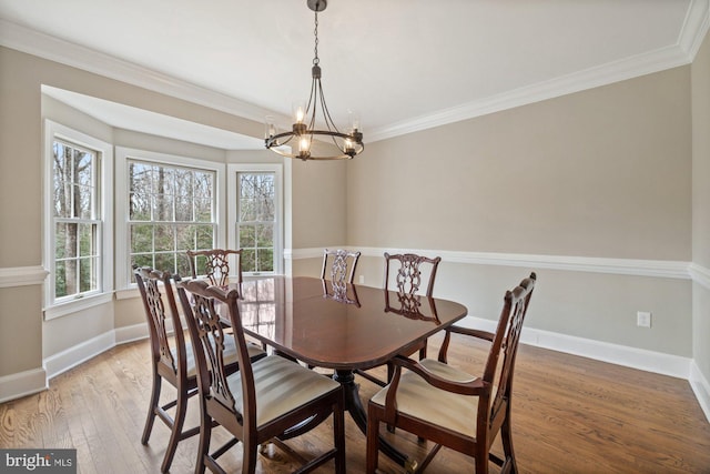 dining space featuring light wood-style floors, a chandelier, ornamental molding, and baseboards