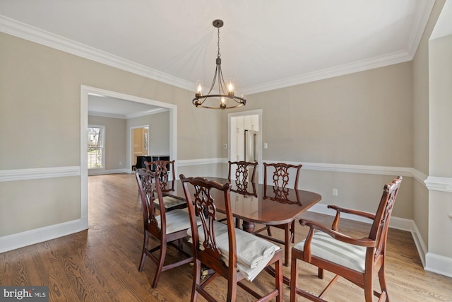 dining room with baseboards, wood finished floors, and crown molding