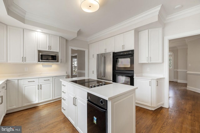 kitchen featuring a kitchen island, wood finished floors, white cabinetry, light countertops, and black appliances