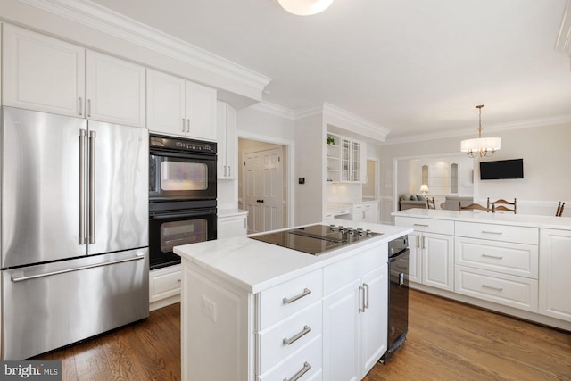 kitchen featuring light countertops, white cabinetry, a kitchen island, wood finished floors, and black appliances