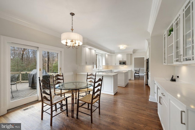 dining room featuring dark wood finished floors, visible vents, and crown molding