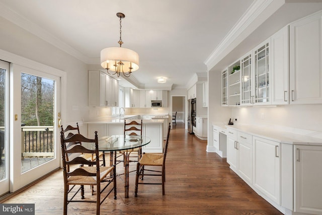 dining area with ornamental molding and dark wood-style flooring