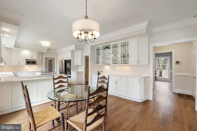 dining space with baseboards, crown molding, an inviting chandelier, and wood finished floors