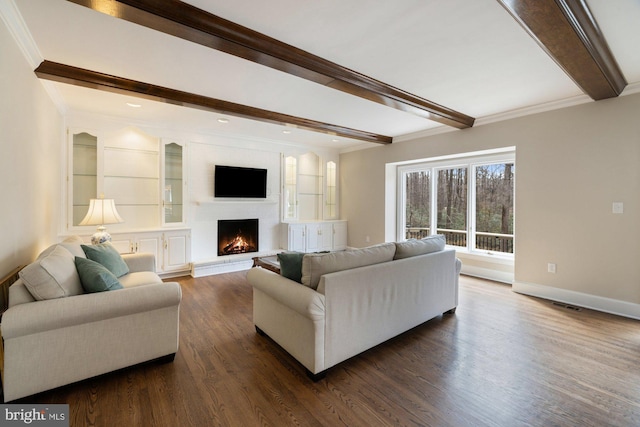 living area with a warm lit fireplace, dark wood finished floors, beam ceiling, and crown molding