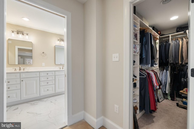 walk in closet featuring marble finish floor and a sink