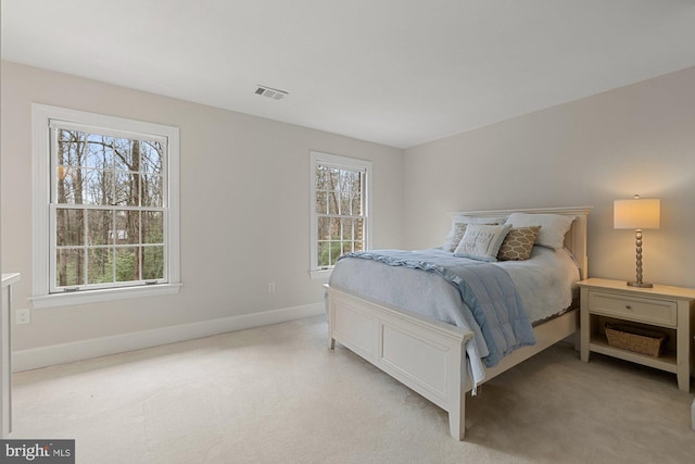 bedroom featuring visible vents, light carpet, and multiple windows