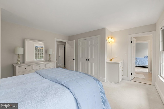 bedroom with baseboards, a closet, and light colored carpet