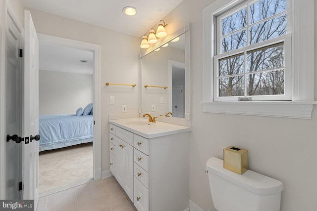 bathroom featuring toilet, ensuite bathroom, vanity, baseboards, and tile patterned floors