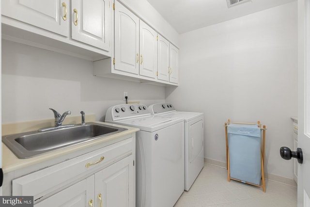 laundry room featuring baseboards, cabinet space, a sink, and washing machine and clothes dryer