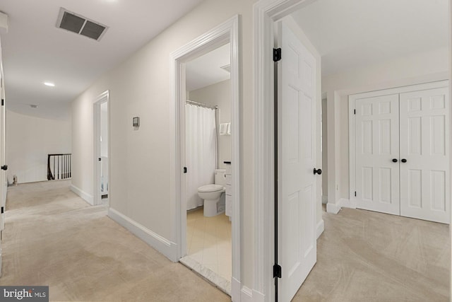 corridor featuring an upstairs landing, baseboards, visible vents, and light colored carpet