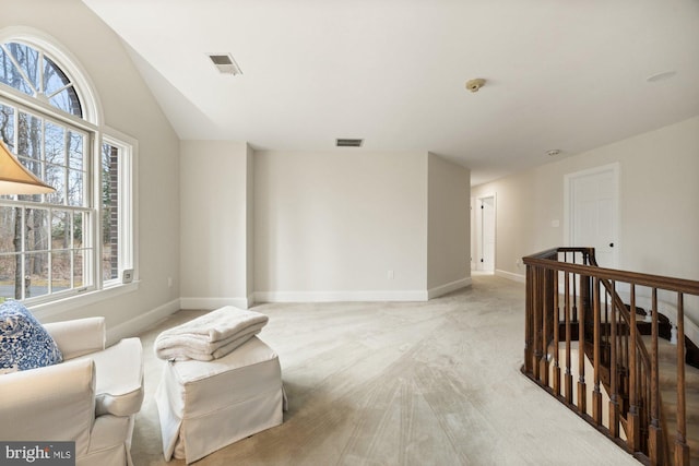 sitting room with baseboards, an upstairs landing, visible vents, and light colored carpet