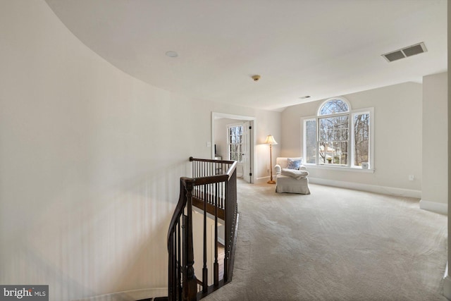 sitting room with baseboards, visible vents, vaulted ceiling, an upstairs landing, and carpet floors