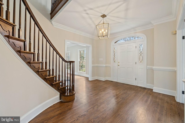 entryway featuring ornamental molding, wood finished floors, a chandelier, baseboards, and stairs