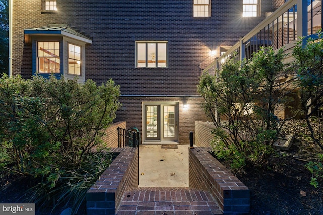 property entrance with a patio, french doors, and brick siding