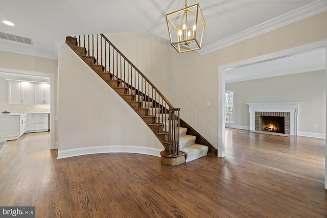 foyer entrance with baseboards, visible vents, wood finished floors, stairs, and crown molding