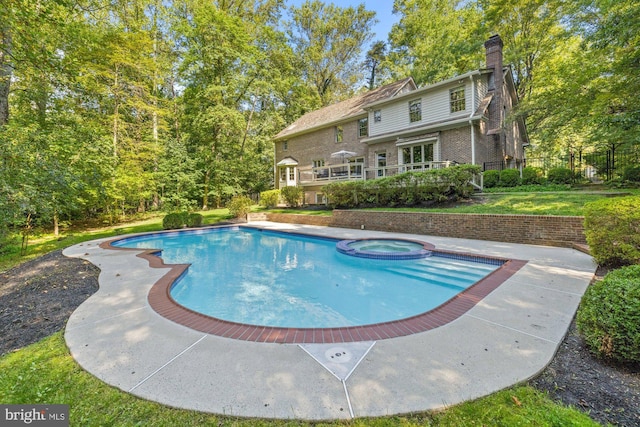 view of swimming pool featuring fence and a pool with connected hot tub