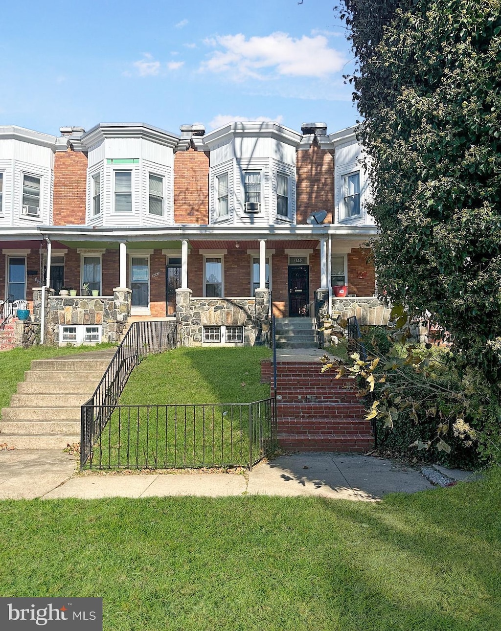 multi unit property with a fenced front yard, a chimney, stairway, covered porch, and a front yard