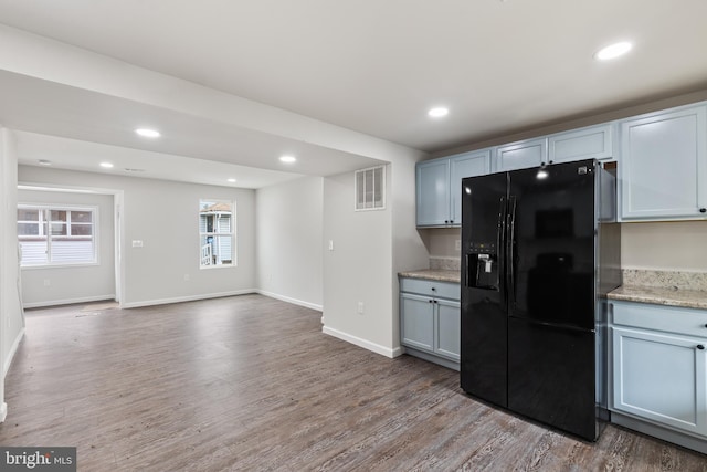 kitchen featuring recessed lighting, wood finished floors, visible vents, baseboards, and black fridge